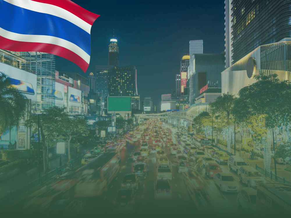 Driving in Thailand: Evening traffic congestion in Thailand with city lights and Thai flag overlay, symbolizing navigating the busy streets with local expertise.