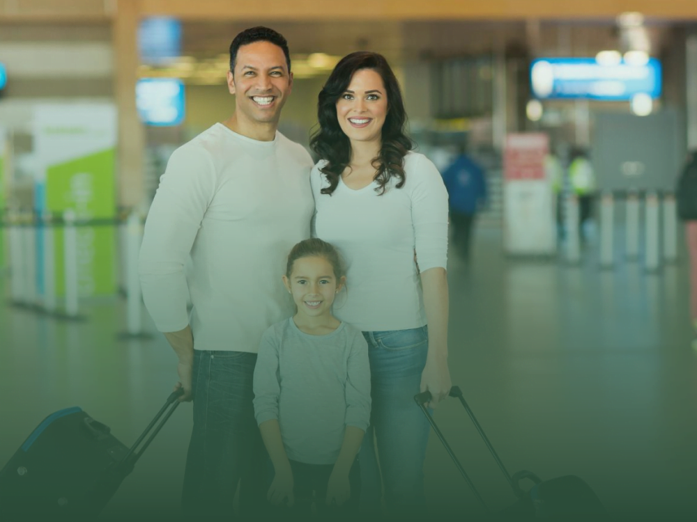 Happy family with luggage at airport, ready to move to Phuket with a family visa.